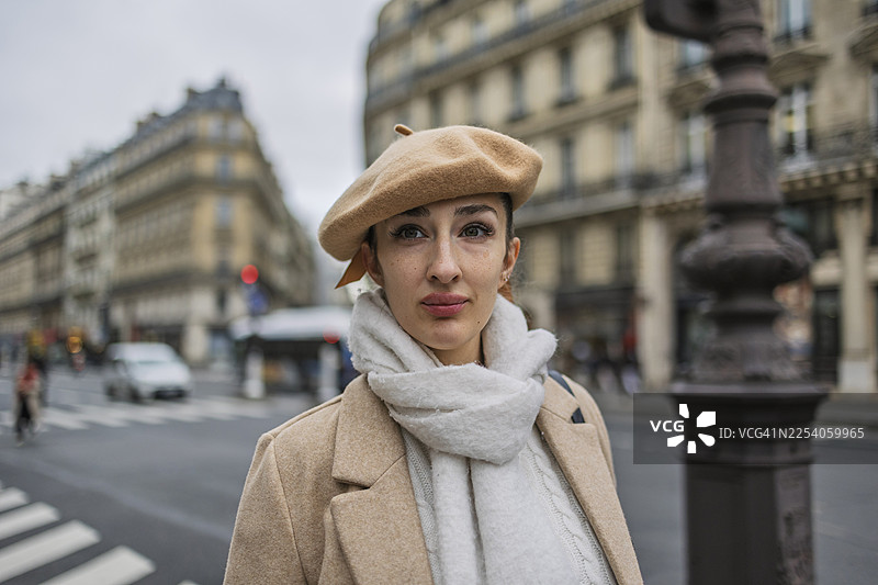 年轻女子戴着贝雷帽和围巾，站在巴黎图片素材