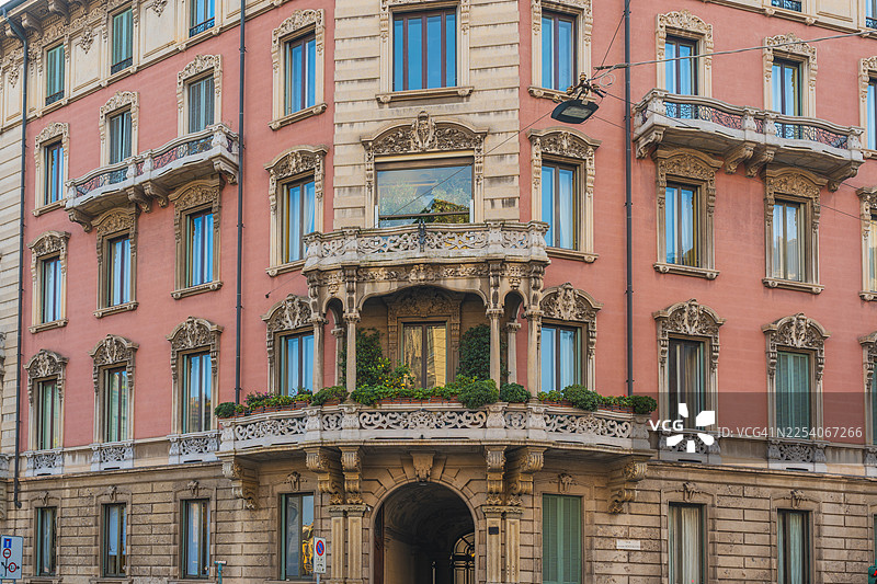 意大利米兰优雅的粉色建筑，带有华丽的阳台和拱形入口图片素材