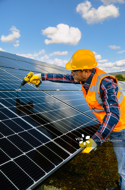 经验丰富的建筑工人：一位老年男子正在用电钻建造金属围栏图片素材