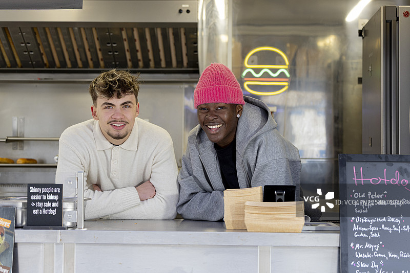 年轻创业团队的肖像，他们经营着一家街头小吃店，站立在现代化的餐车里。图片素材