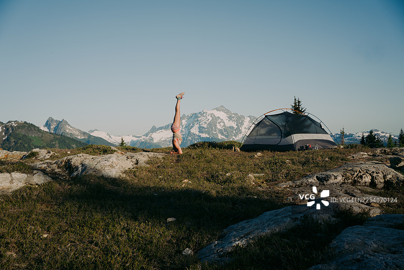帐篷和山峦背景下的女性头倒立图片素材