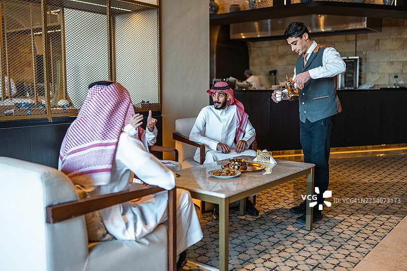 中东男子享受咖啡，服务员殷勤周到图片素材