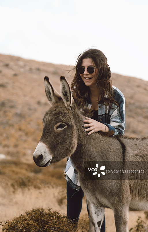 乡村风景中，快乐的年轻女子与驴的肖像图片素材