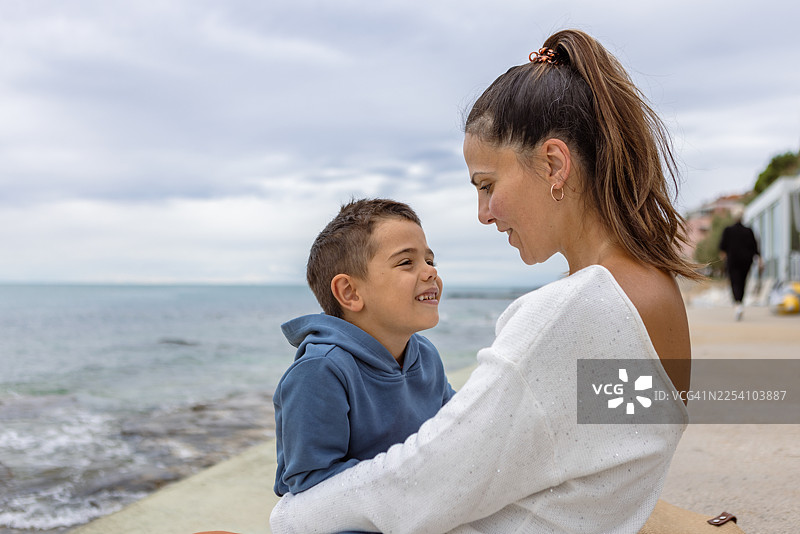 海边的喜悦：母子俩在海岸边共享天伦之乐图片素材