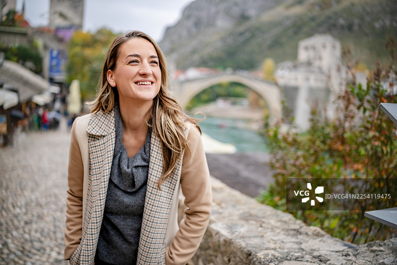 秋季，游客在波斯尼亚和黑塞哥维那莫斯塔尔的古桥上欣赏风景图片素材