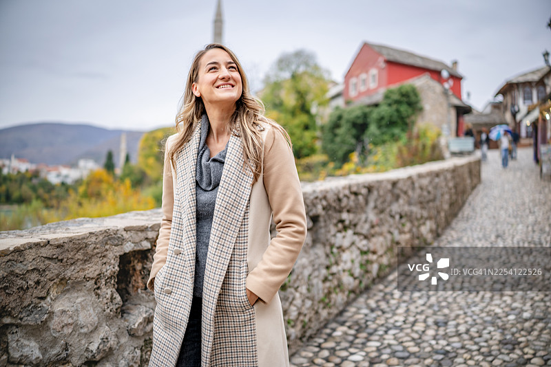年轻女子在波斯尼亚和黑塞哥维那的莫斯塔尔漫步，在历史建筑附近的鹅卵石小径上享受着她的一天图片素材