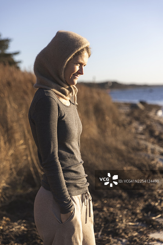 戴着针织帽和羊毛保暖内衣的女性在海滩上图片素材