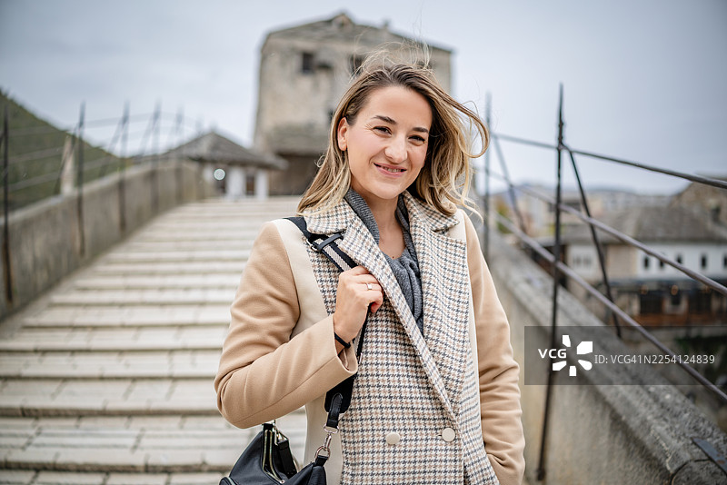 一个年轻女子在多云的日子里，在波黑莫斯塔尔游玩时微笑着图片素材