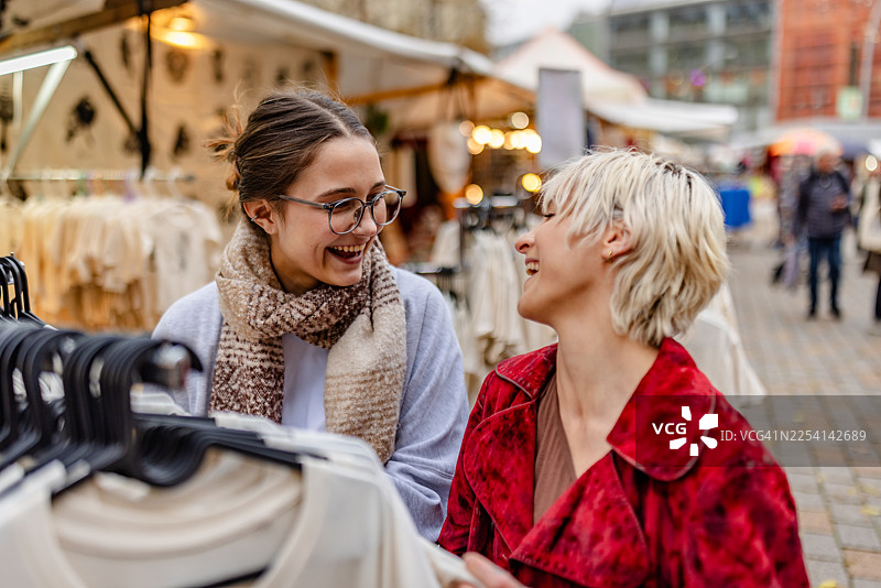 朋友们在柏林的市场购物，微笑着挑选衣物图片素材