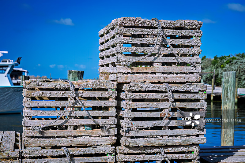 马达加斯加钥匙岛上的捕虾笼堆放在渔船码头上，上面覆盖着藤壶图片素材