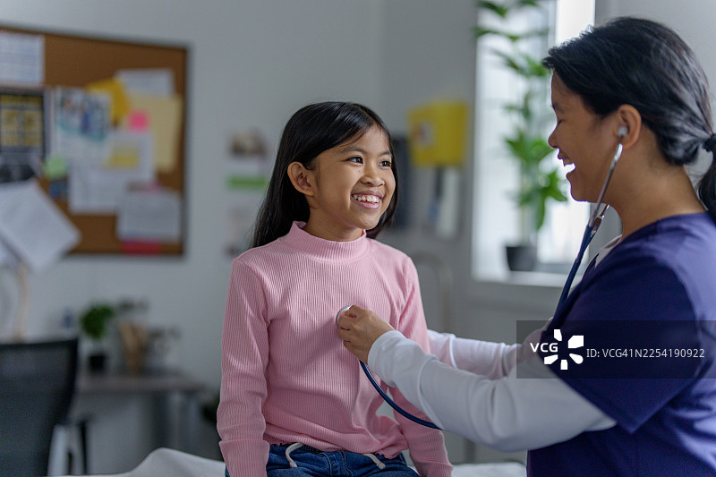 亚洲女孩患者接受护士友善的听诊检查图片素材
