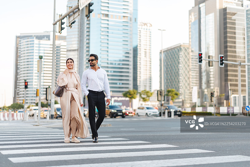 中东男子和高加索女子在迪拜的城市人行横道上漫步图片素材