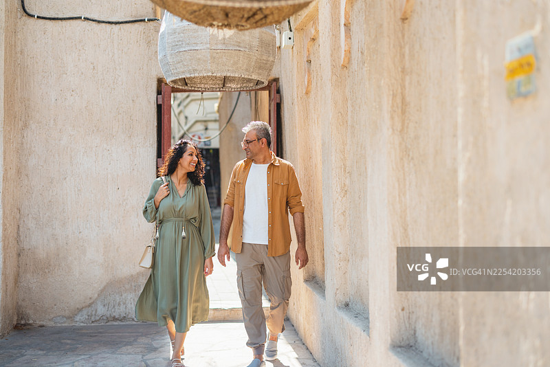 一对富有冒险精神的中东夫妇在阿尔法希迪阳光明媚的古老小巷中探索图片素材