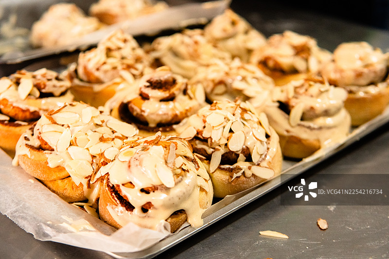 新鲜出炉的肉桂卷，淋着甜美的糖霜，撒着切片的杏仁图片素材