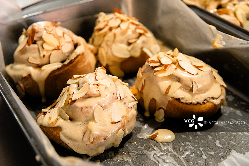 烤盘上淋有糖霜和切片杏仁的肉桂卷图片素材