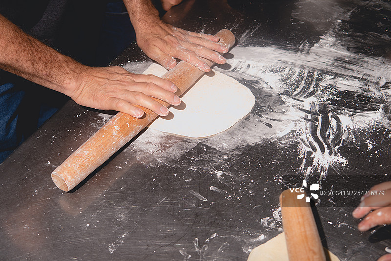 一个人用木质擀面杖擀面团图片素材