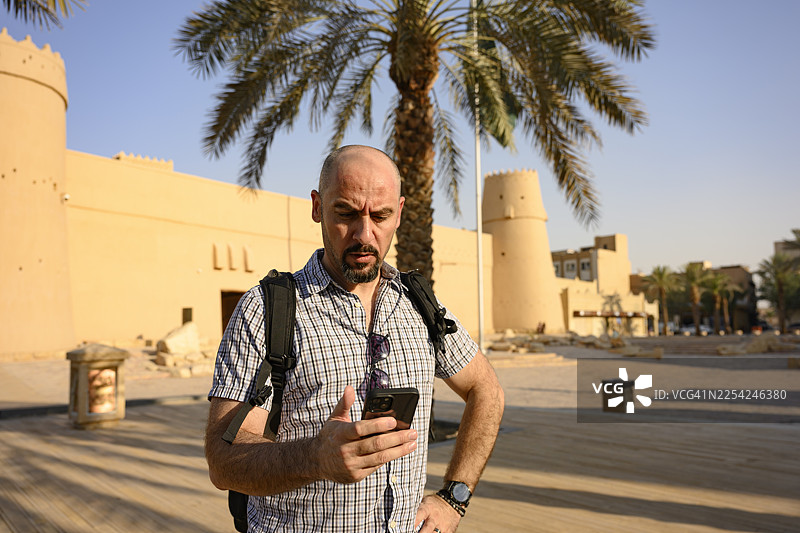 一名男性游客在沙特阿拉伯利雅得使用智能手机参观马斯马克堡图片素材