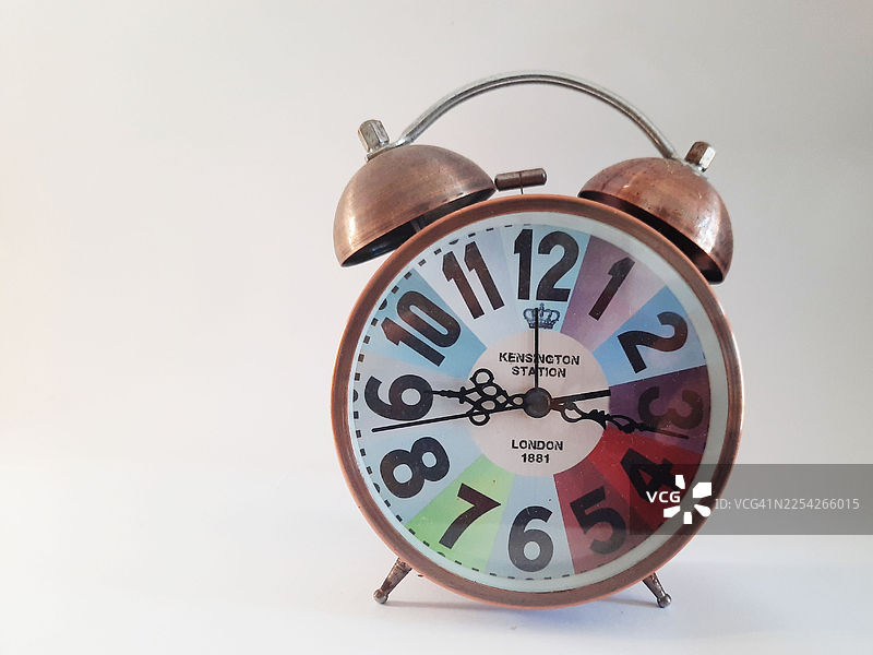 复古铜色双铃闹钟，带彩色表盘，背景为白色图片素材