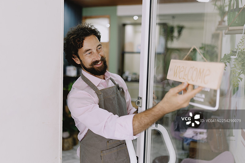 咖啡馆或花店老板开店并放置欢迎标志图片素材