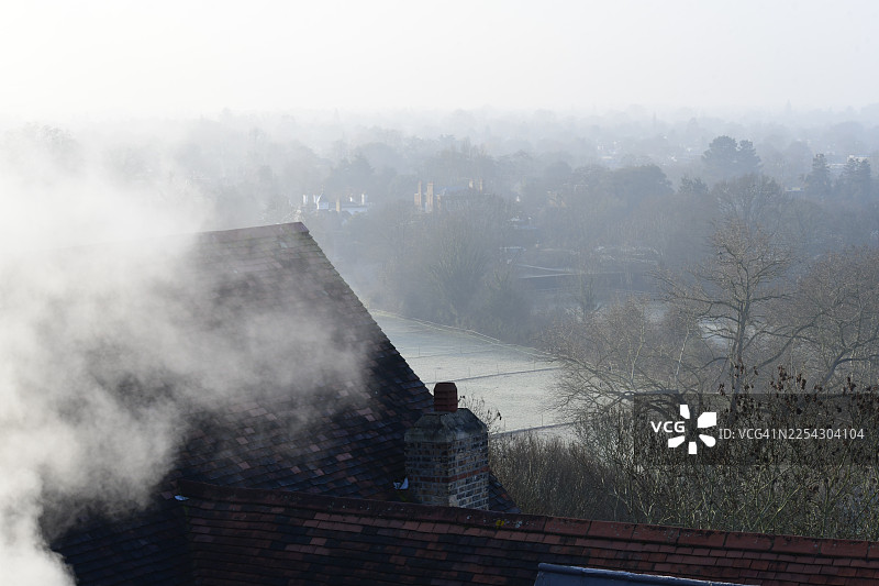 河畔屋顶和烟囱在薄雾与烟尘中的剪影图片素材