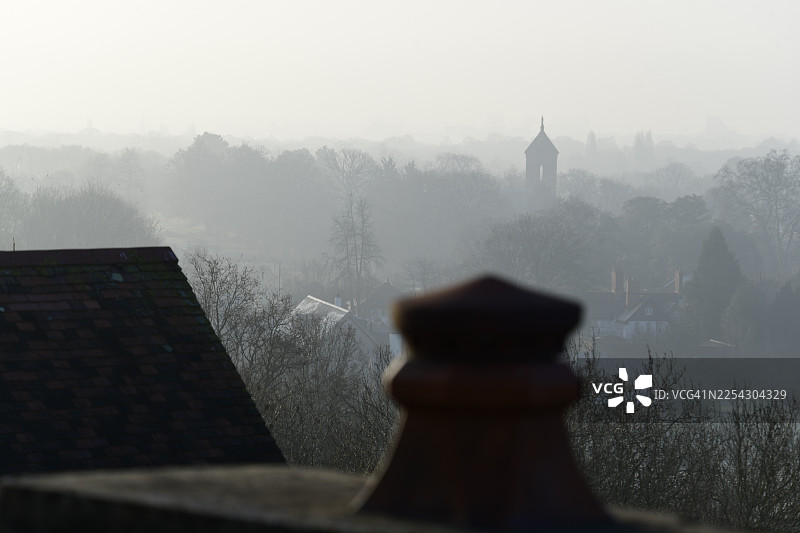 雾气和烟雾中的河畔屋顶和烟囱剪影图片素材