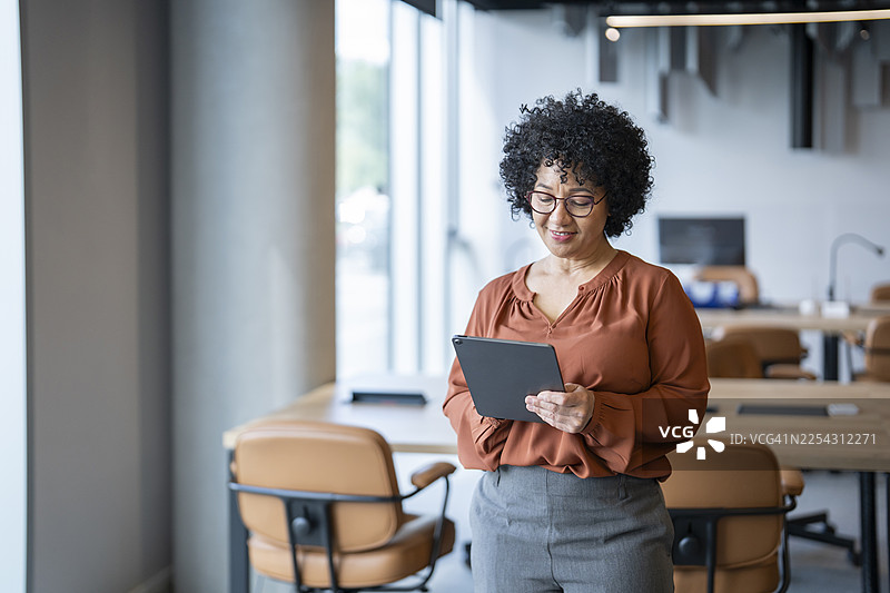 自信成熟的女商人在现代办公室使用平板电脑图片素材