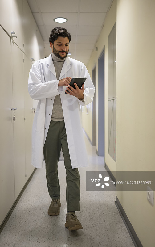 年轻科学家在医学院的走廊/楼梯间使用数码平板电脑图片素材