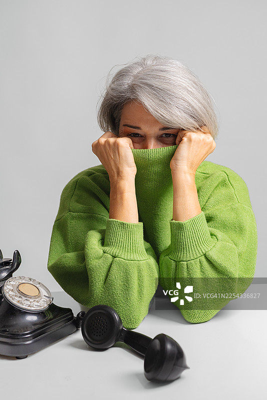 一位年长的女士将脸藏在套头衫后面图片素材