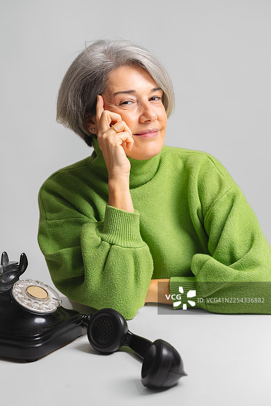 老年妇女微笑着使用老式旋转电话图片素材