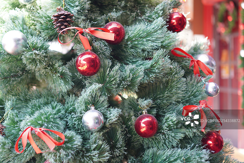 装饰好的圣诞绿树，装饰品有金色礼品盒，背景虚化有叶子图片素材