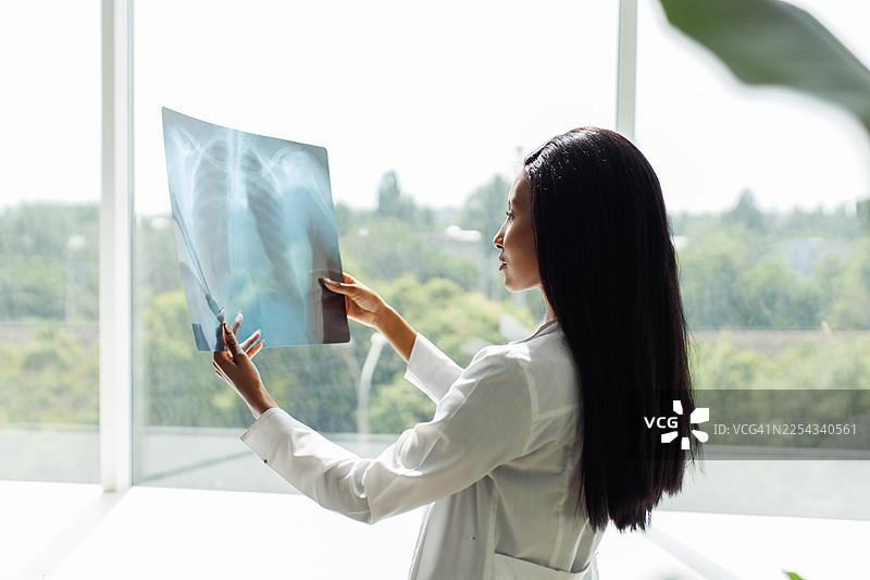 明亮的诊所里，一位医务专业人员正在检查X光片图片素材
