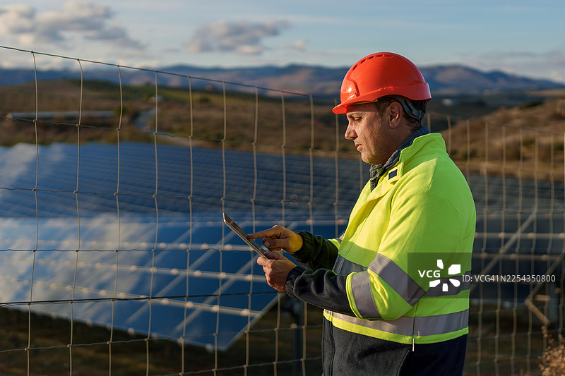 中年工程师在太阳能电池板农场使用平板电脑工作图片素材