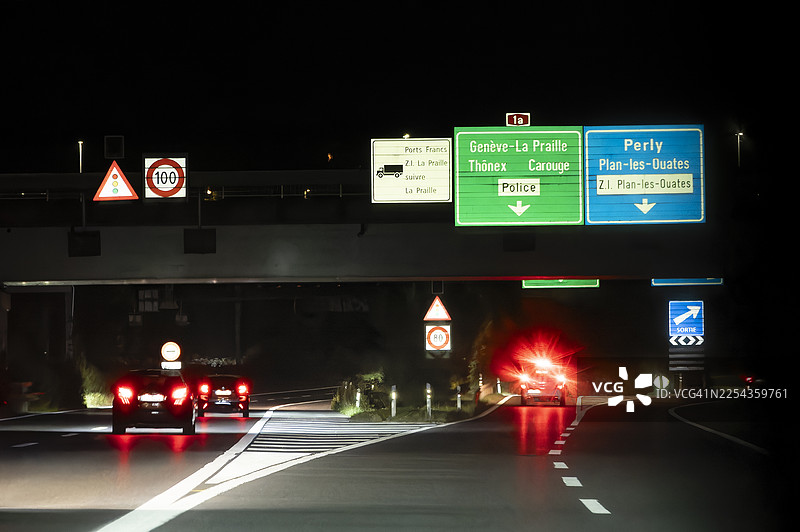 从车内看，瑞士高速公路上的夜间车流和标志。图片素材