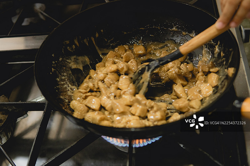 在燃气灶上用炒锅烹饪鸡肉炒菜图片素材