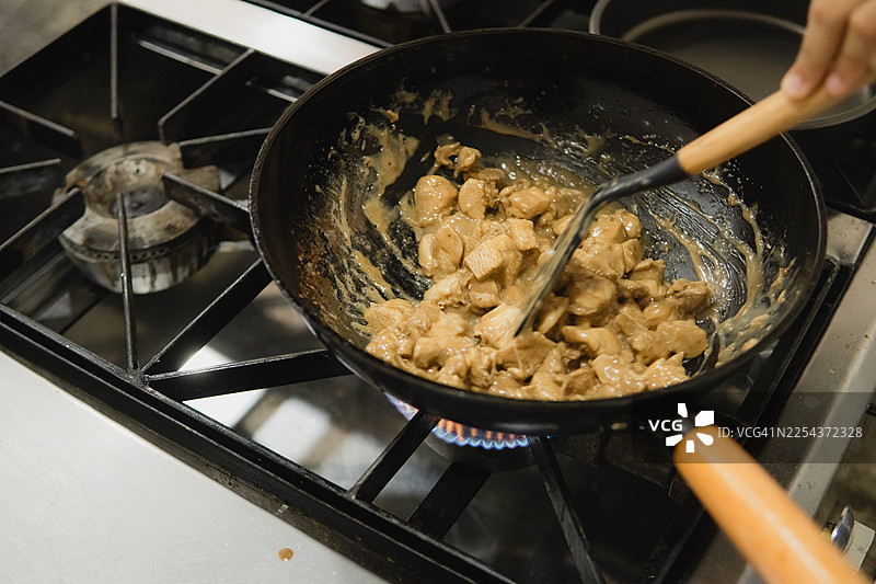 在餐厅厨房的燃气灶上用酱汁烹饪鸡肉图片素材