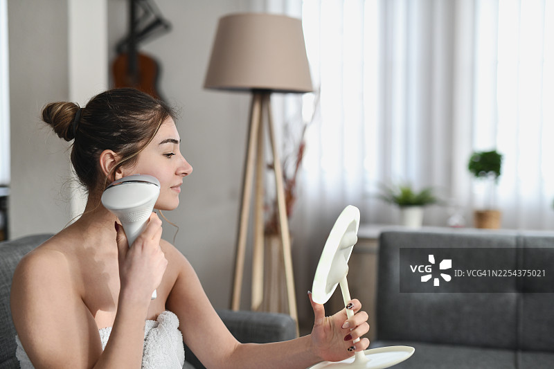 女性使用脱毛器进行面部美容，作为护肤流程的一部分图片素材