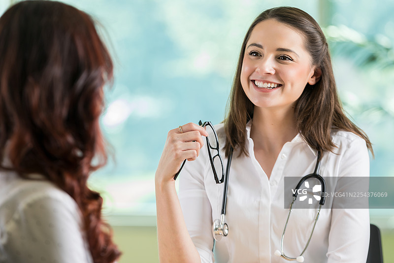 友好的医生正在咨询病人，他手里拿着眼镜，身上戴着听诊器图片素材