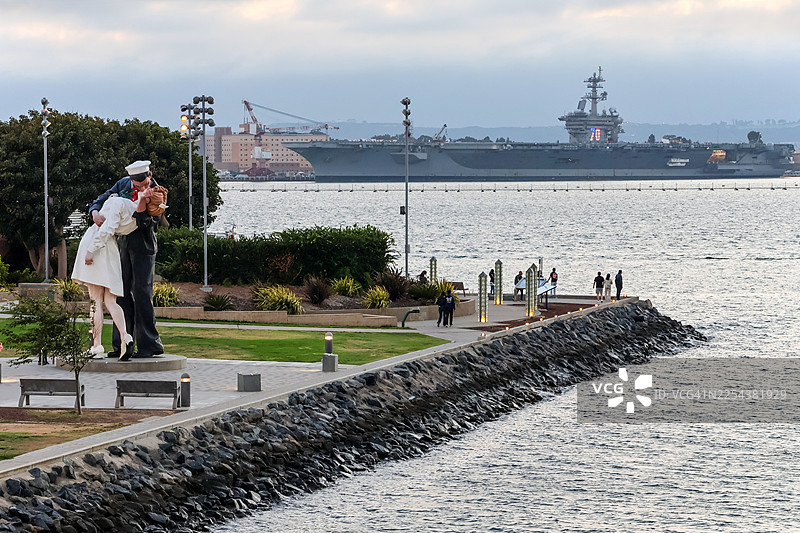 背景为圣迭戈的卡尔·文森号航空母舰，前景是“无条件投降”雕塑图片素材