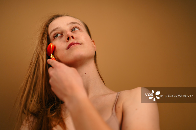 美丽的年轻女子在护肤过程中使用玉石滚轮图片素材