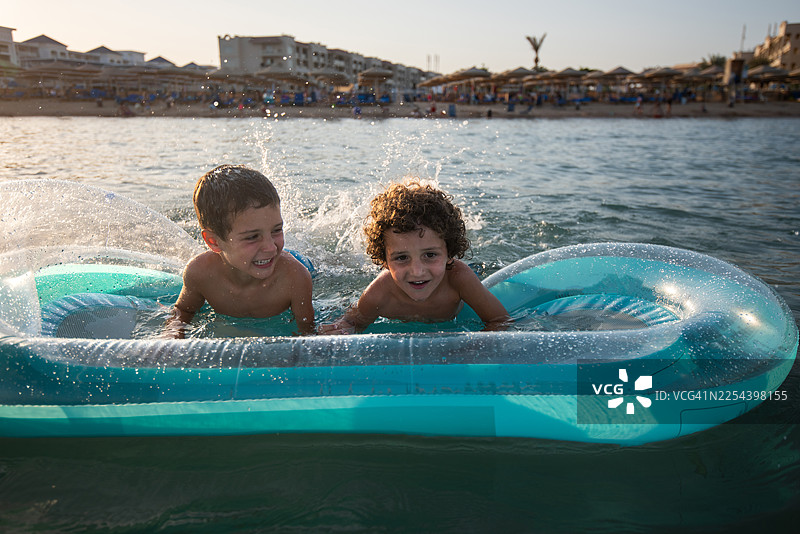 孩子们在日落时分乘充气船在海上玩耍。图片素材