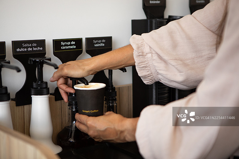 一位年轻女子正在准备从智能售货机购买的咖啡图片素材