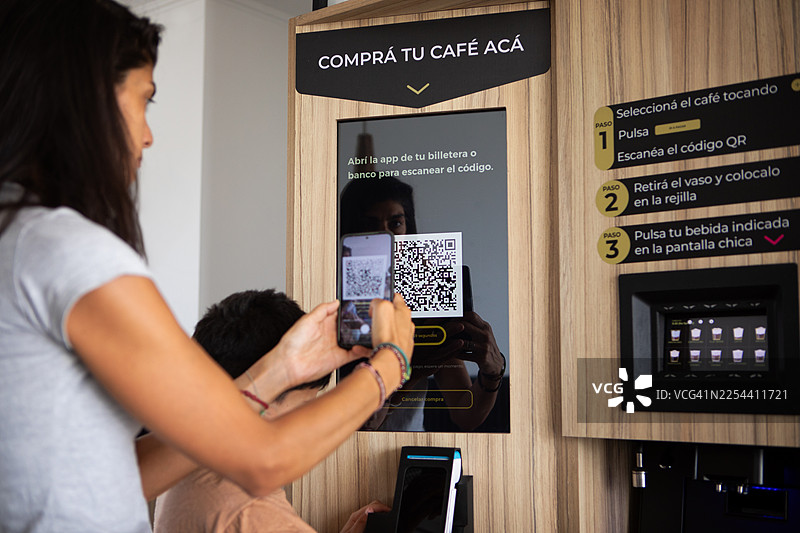 一位母亲和她的儿子正在使用人工智能和机器人技术从自动售货机购买咖啡图片素材