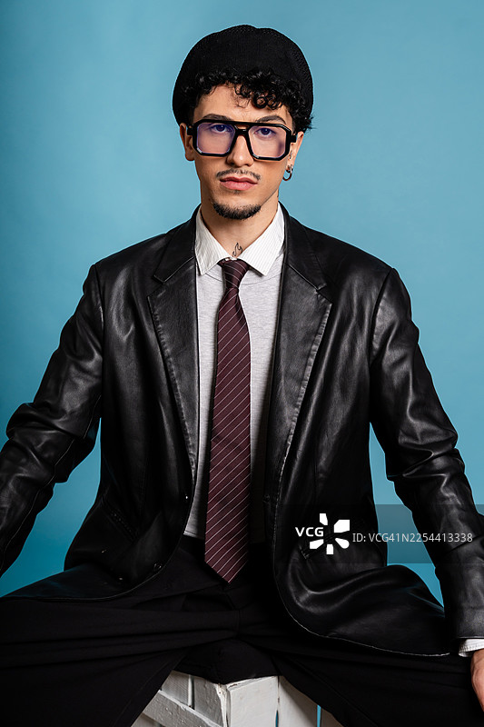 戴着贝雷帽、眼镜、皮夹克和领带的年轻成年男子图片素材