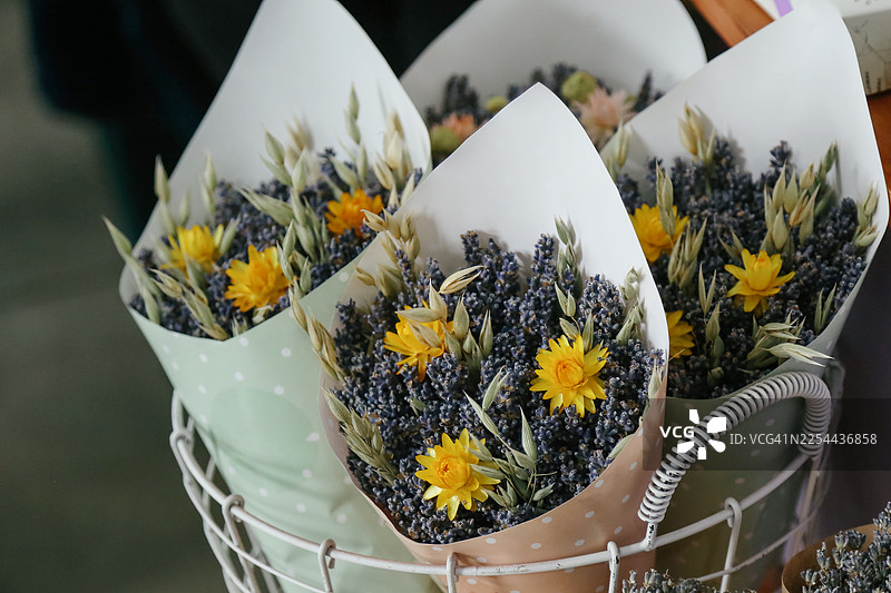 紫色的石南花、薰衣草和野花花束用棕色纸包裹，准备在当地花店出售图片素材