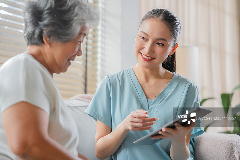 亚洲年轻的心理健康专家，为老年女病人提供上门医疗服务，富有同情心地进行咨询、身体护理和老年病治疗。图片素材