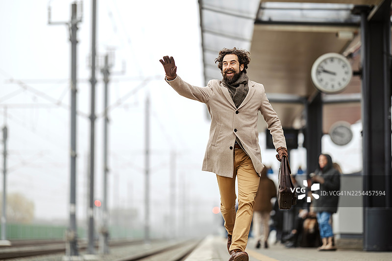 快乐的男人在火车站台奔跑挥手图片素材