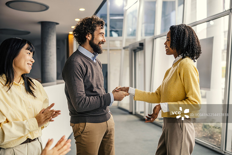 多元化的商业团队伙伴们在庆祝成功时握手图片素材