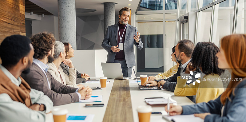 一位成熟的企业家向多元化的商业团队展示图片素材