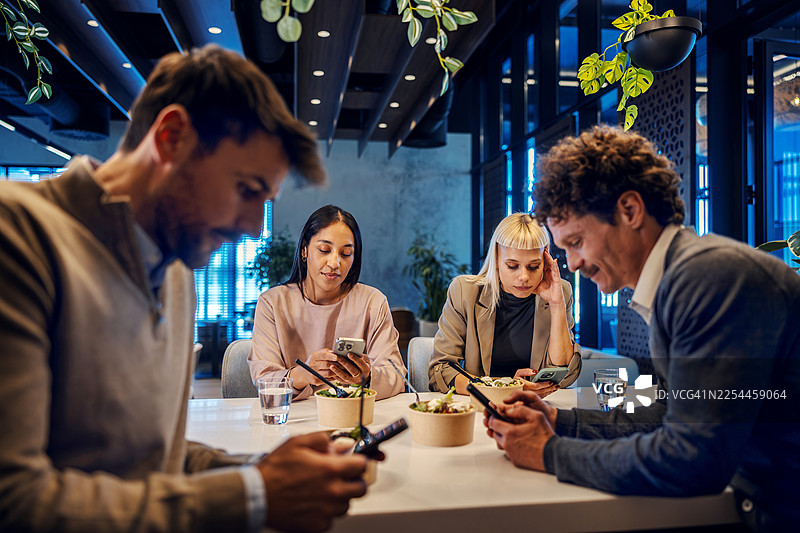 同事们在办公室咖啡馆的午休时间使用智能手机图片素材