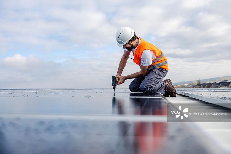 工人正在建筑屋顶安装太阳能电池板图片素材